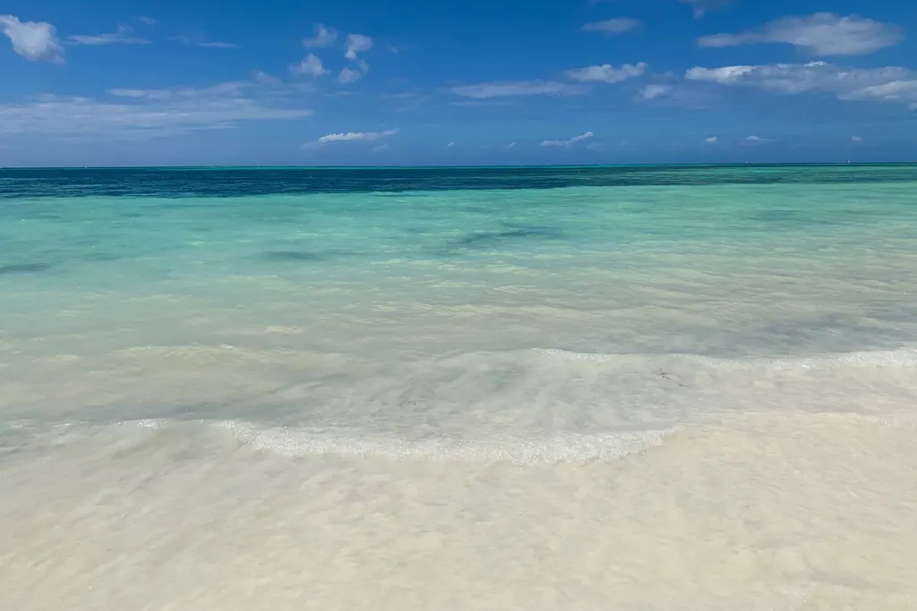 Klares, türkisfarbenes Wasser und heller Sand am Strand von Kiwengwa