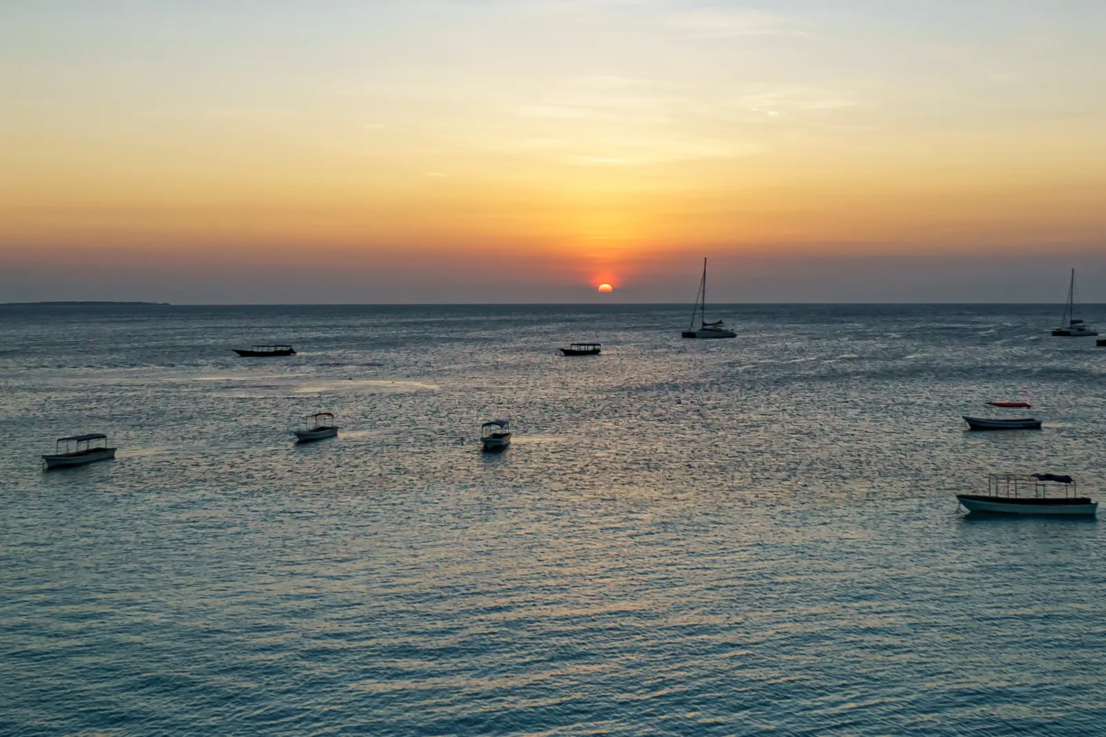 Sonnenuntergang über dem Meer bei Nungwi, davor mehrere ankernde Boote
